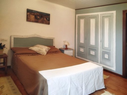 Habitación con cama doble, mesita de noche y armario de puertas claras.