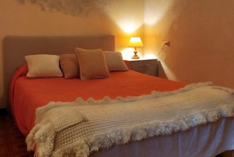 Dormitorio con cama matrimonial, muebles claros y armario de puertas blancas y azules.