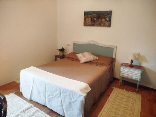 Habitación con una cama sencilla, mesita de noche y decoración minimalista.